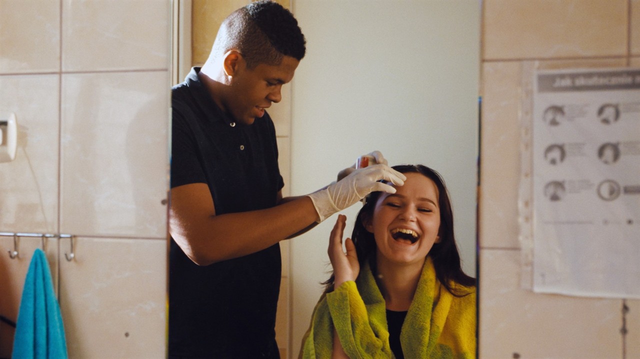 A teenage boy dyes a teenage girls hair